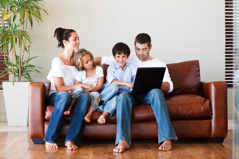 Happy family playing together with a laptop on a sofa